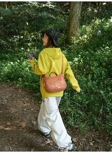 Vue lifestyle d'un sac messager orange en nylon imperméable porté dans un cadre extérieur