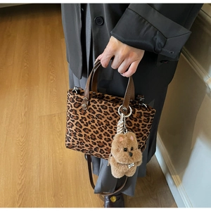 Dettaglio della borsa in pelle scamosciata leopardata con manici in pelle e ciondolo a cane