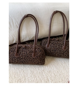 Detail of leopard print cylinder bag featuring contrast stitching and leather straps