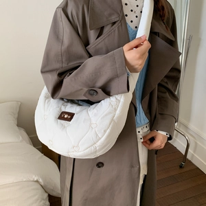 Quilted heart-pattern crescent bag shown in a cozy home setting with model outfit