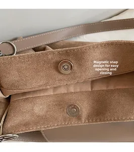 Detailed close-up of brown suede bag featuring a magnetic metal buckle closure system