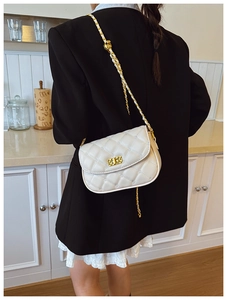 Detailed side view of white quilted crossbody bag with metal chain strap on model
