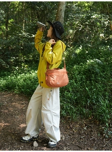 Détail d'un sac bandoulière orange à carreaux imperméable dans une scène de randonnée