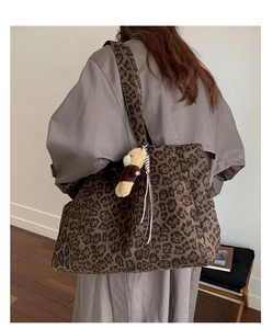 Detailed view of leopard print tote bag with bear charm on a model's shoulder