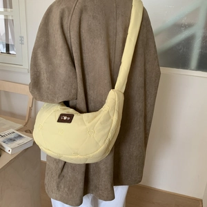 Detailed heart-quilted yellow crescent bag shown in use on a model's shoulder
