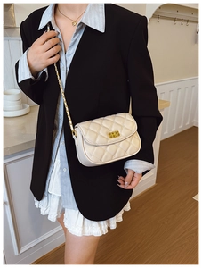 Detail of a beige quilted chain crossbody bag with a gold rectangular rotating lock