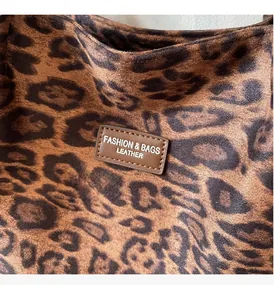 Detailed close-up of leopard print tote bag fabric with stitched leather logo patch