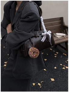 Détail du sac Boston marron avec poignée à nœud en dentelle et breloque donut
