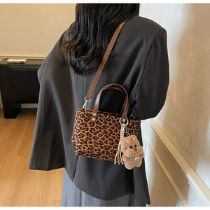 Detailed close-up of leopard print handbag with brown faux leather handle and bear charm