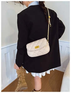 Close-up of beige quilted leather crossbody bag with gold metal chain strap on model