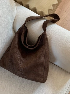 Sac fourre-tout en daim marron avec motif gaufré posé sur un canapé d'intérieur