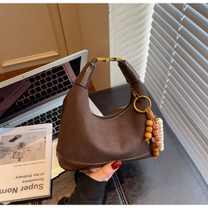 Détail du sac croissant en daim marron foncé avec fermoir doré et perles en bois