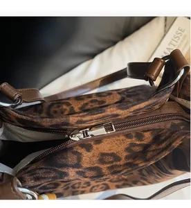 Detail of silver zipper closure on leopard print tote bag with brown faux leather strap