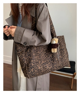 Detailed view of leopard print tote bag with thick shoulder strap and bear charm