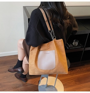 Detail of caramel suede tote bag with leather pocket and metal chain strap on shoulder