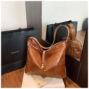Détail d'un grand cabas vintage marron avec breloque dorée et finition en cuir brillant