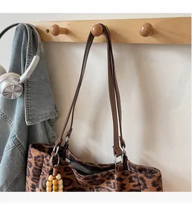 Detailed leopard print tote bag with brown straps and wood bead pendant on a clothes rack