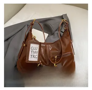 Detail of dark brown patent leather hobo bag with gold hardware and clochette tag