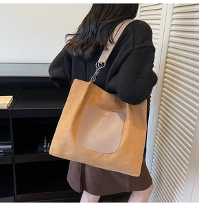 Close-up of caramel brown suede tote bag with leather pocket and metal chain strap
