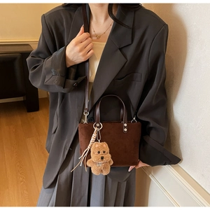 Dettaglio mini borsa a secchiello in pelle scamosciata marrone con ciondolo a cane