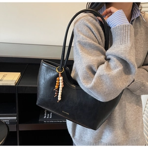 Détail du grand sac cabas noir avec pendentif en perles de bois et logo doré
