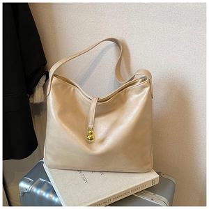 Détail du sac cabas en cuir doré champagne avec pendentif métallique pour le style urbain