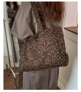Detail view of large leopard print tote bag worn over the shoulder on a model