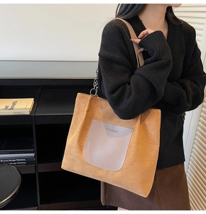 Detail of suede tote bag with brand logo patch and elegant silver chain strap