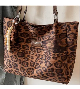 Detail of leopard print tote bag with brown leather patch and vintage wooden bead charm