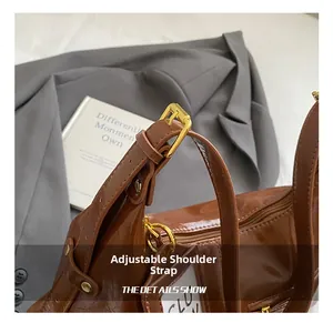 Close-up of adjustable shoulder strap with gold buckle on brown patent leather tote bag