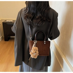 Detail of vintage suede bucket bag with leather handle and cute teddy bear charm