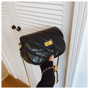 Detail of black quilted leather crossbody bag featuring gold skull charm and chain strap