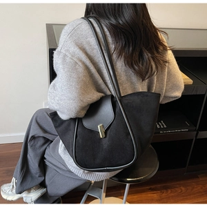 Detail of black tote bag with smooth leather suede panels and golden metal lock