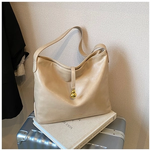 Détail d'un sac cabas en similicuir beige avec breloque dorée sur un fond minimaliste