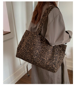 Close-up of leopard print tote bag with wide shoulder strap worn with trench coat