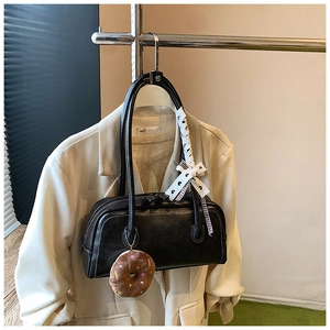 Détail du sac baguette noir avec charme en peluche donut et ruban en dentelle