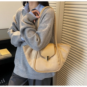 Detailed close-up of textured beige suede tote bag with leather trim and gold metal lock
