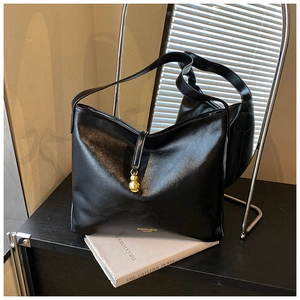 Détail du sac hobo en cuir noir avec breloque gourde dorée et lettrage logo en métal