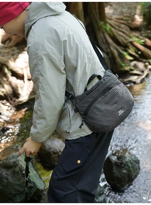 Gros plan d'un sac à bandoulière imperméable à damier noir et blanc en forêt