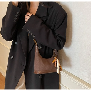 Détail d'un sac demi-lune en daim marron avec pendentifs rétro en perles et patchwork cuir