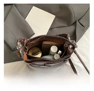 Interior view showing capacity of brown leather bucket bag with phone and cosmetics
