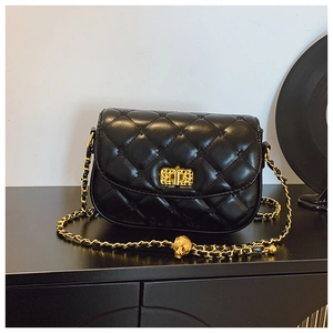 Close-up of black quilted crossbody bag with gold star rivets and metal turn-lock