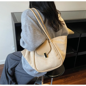 Close-up of beige suede tote bag featuring a black and gold metal buckle and leather trim
