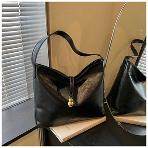 Détail d'un sac bandoulière en cuir noir avec pendentif gourde dorée et logo