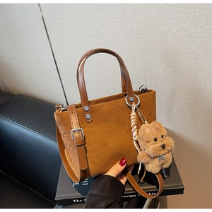 Dettaglio borsa a secchiello in camoscio marrone vintage con tracolla e ciondolo a cane