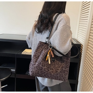 Detail of leopard print tote bag with beaded charm and black leather strap on shoulder