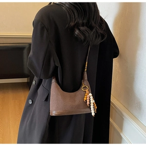 Sac hobo marron en daim vintage avec breloques de perles bohèmes porté à l'épaule