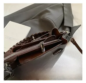 Detail of premium brown leather bucket bag with silver dual zippers and metallic hardware
