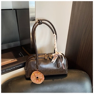 Détail du sac baguette marron foncé avec breloque donut en peluche et nœud en soie