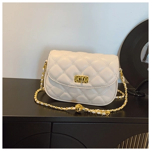 Detail of beige quilted flap bag with golden twist lock and chain strap on a black surface